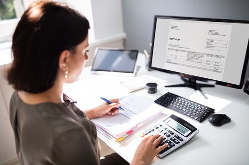 Woman working at computer with calculator